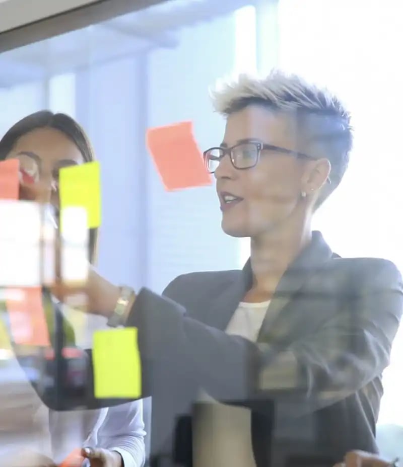 woman-putting-up-sticky-notes woman-putting-up-sticky-notes